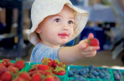 child with strawberry at oregon farmer's market