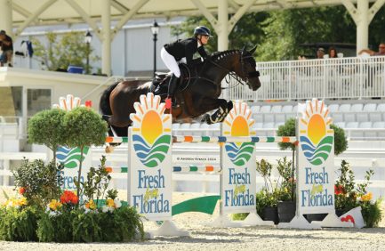 Rider jumps over bars at World Equestrian Center with "Fresh From Florida" signs on the obstacles