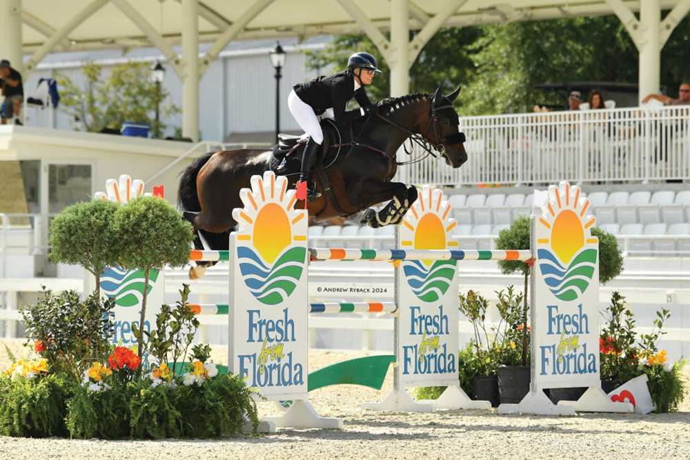 Rider jumps over bars at World Equestrian Center with "Fresh From Florida" signs on the obstacles