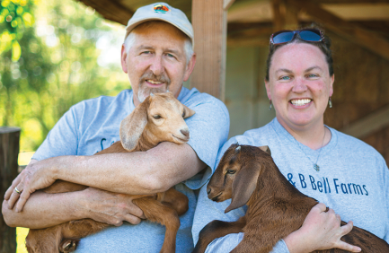 Brian and Susan Bell each holding a goat at their farm, S&B Bell Farms