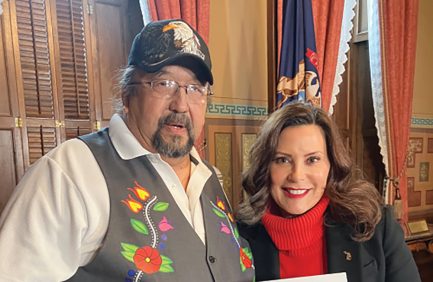Roger LaBine and Gov. Gretchen Whitmer hold the bill for Manoomin to become the Michigan state grain